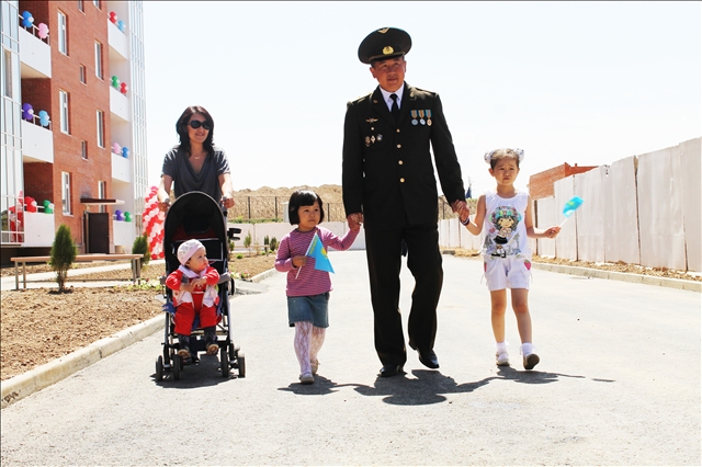 Офицер Кайрат Пернебаев вместе со своей женой и тремя детьми гуляют во дворе нового дома