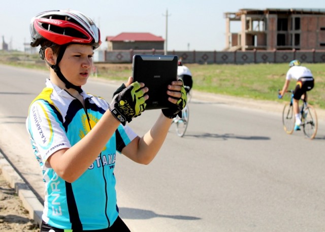 Юный спортсмен решил запечетлить выступление  велогонщика из своей команды.