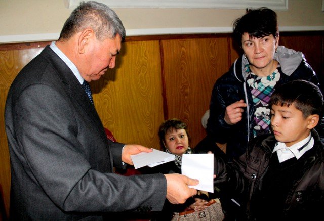 Председатель южно-казахстанского филиала демократической партии "Ак жол", Анарбек Орман вручает конверты школьникам из малоимущих семей