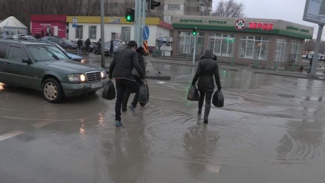 Потоп на проезжей части пересечений улиц Жибек-Жолы и Рыскулова. Пешеходы, пытаясь не намочить ног, переходят дорогу вприпрыжку.  