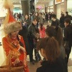 Девушка в национальном костюме раздает конфеты